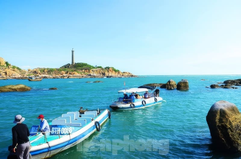 Kỳ thú những cung đường bộ xuyên biển - Ảnh 7. Những chiếc thuyền lướt nhẹ trên mặt biển màu ngọc lam gần bờ đá, phía xa là ngọn hải đăng trên ngọn đồi dưới bầu trời xanh trong vắt.