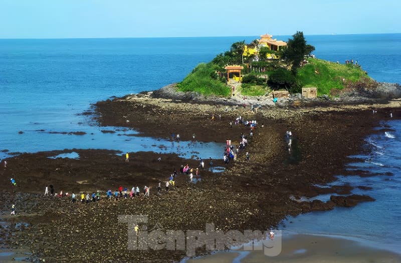 Kỳ thú những cung đường bộ xuyên biển - Ảnh 12. Mọi người đi bộ dọc theo con đường đá gồ ghề đến một hòn đảo nhỏ xanh mướt, nơi có một ngôi đền, bao quanh là đại dương xanh thẳm dưới bầu trời trong vắt.