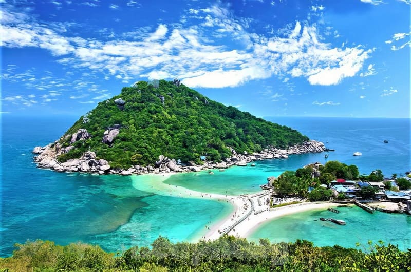 Kỳ thú những cung đường bộ xuyên biển - Ảnh 13. Một hòn đảo xanh tươi với dải bãi biển cát trắng mịn màng, bao quanh là làn nước màu ngọc lam dưới bầu trời xanh trong vắt điểm xuyết những đám mây rải rác.