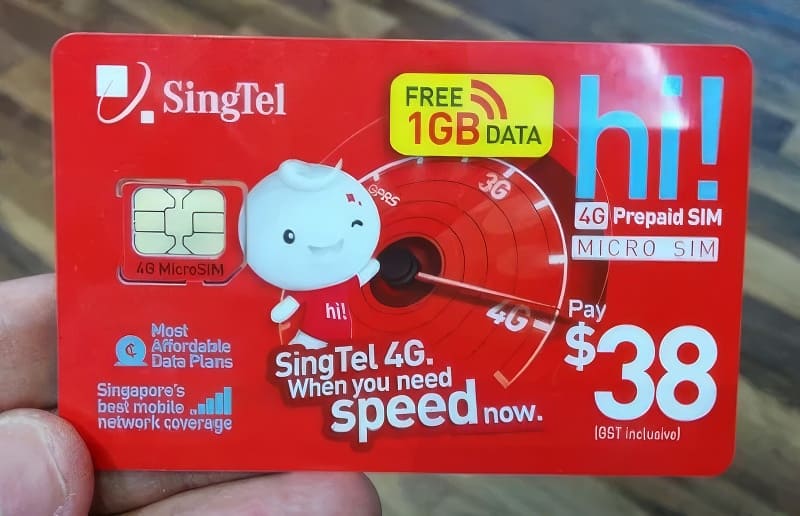 Bao bì thẻ SIM Singtel màu đỏ với dòng chữ "hi!" và "SIM trả trước 4G". Thẻ SIM có ưu đãi tặng 1GB dữ liệu miễn phí và giá 38 đô la. Thiết kế năng động với hình linh vật tươi cười.